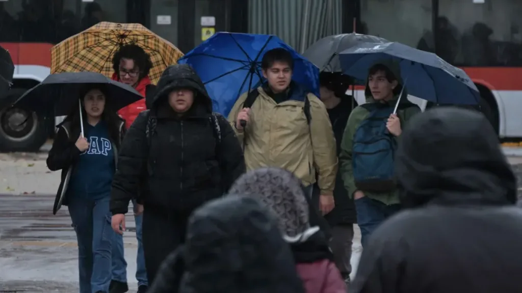 Personas caminando bajo la lluvia por la Alameda